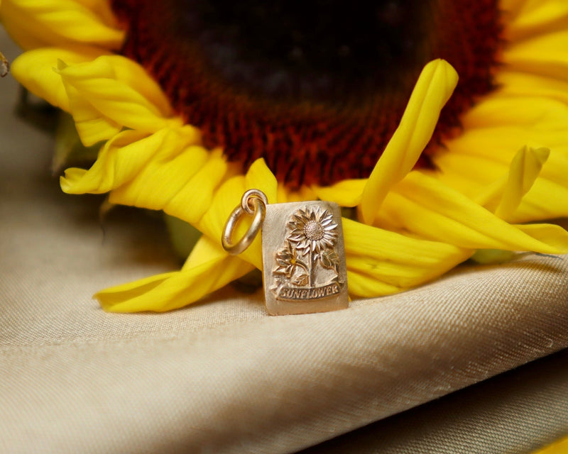 Sunflower charm on a yellow sunflower with a beige background